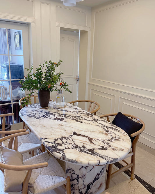 Calacatta Viola dining table with an elongated rounded top and two curved semi-cylinder bases in a dining room
