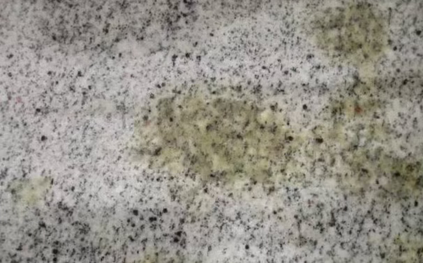 Yellow oil discoloration on a speckled natural stone surface