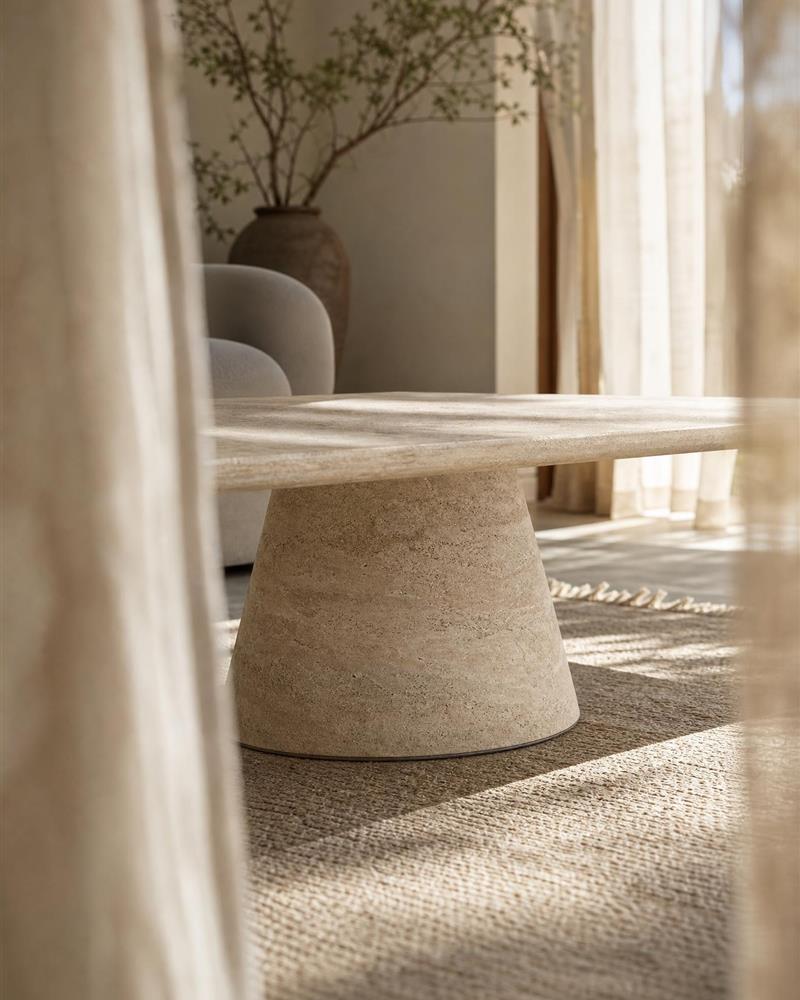 Conical travertine pedestal base in soft natural window light